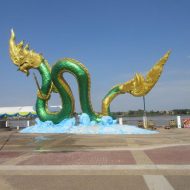 Phaya Nak emerging from the murky waters of a river