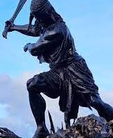 Statue of Bantong in traditional warrior attire, adorned with tribal patterns.