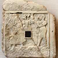 Worn engraving of Ninhursag etched into stone, featuring intricate ancient patterns.